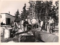 Group of workers around machine with photographer looking at camera