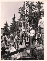 Group of workers around machine (vertical image)
