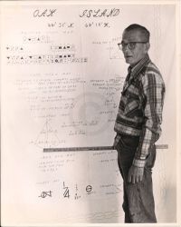 J. Goodman standing next to various calculations on Oak Island